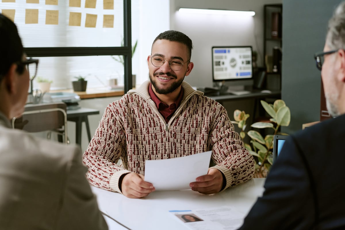 Kandidaat in gesprek met twee professionals tijdens een kennismakingsgesprek in een modern kantoor